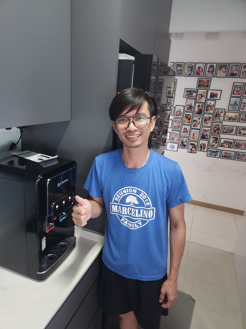 A man gives a thumbs-up next to a sleek Sterra water dispenser.