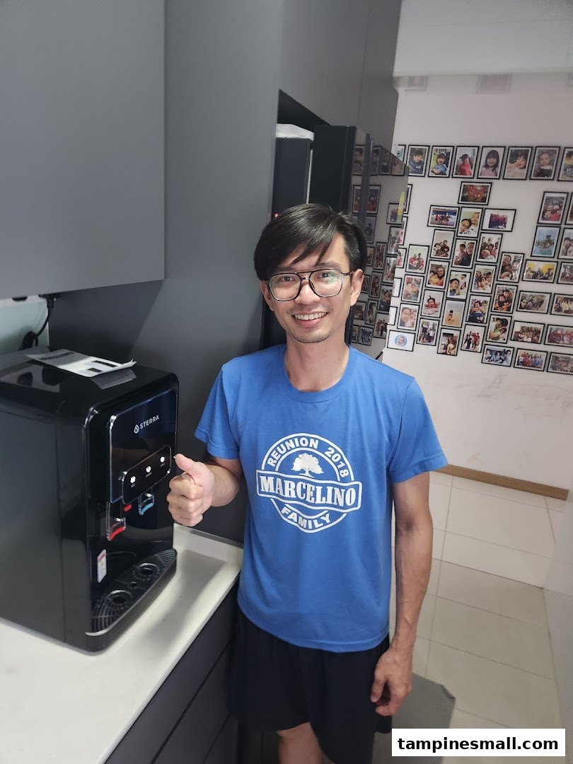 A man gives a thumbs-up next to a sleek Sterra water dispenser.