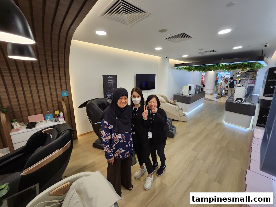 Three individuals pose inside Sterra Singapore, surrounded by modern massage chairs and wellness products.