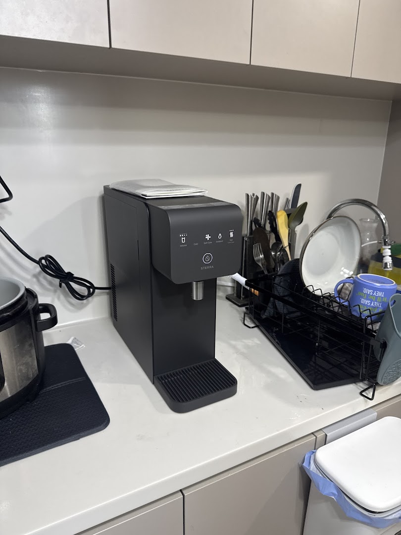 A sleek black Sterra water dispenser on a modern kitchen countertop.