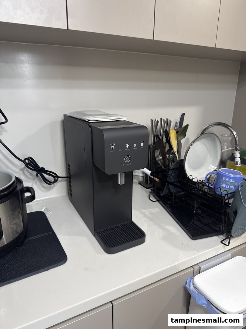 A sleek black Sterra water dispenser on a modern kitchen countertop.
