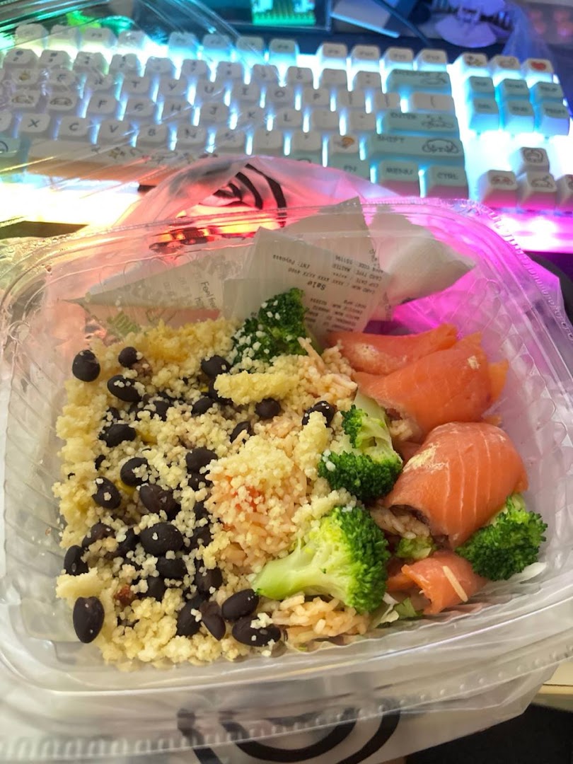 A healthy takeaway bowl from Stuffd featuring couscous, black beans, broccoli, and salmon.