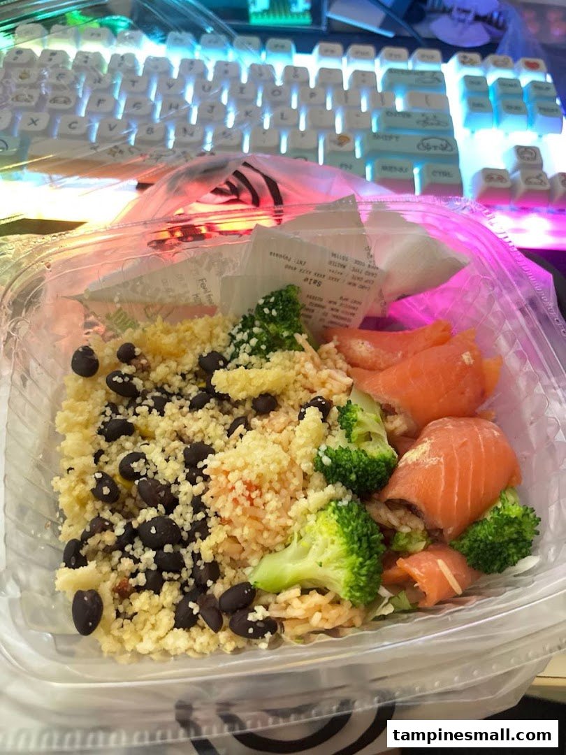 A healthy takeaway bowl from Stuffd featuring couscous, black beans, broccoli, and salmon.