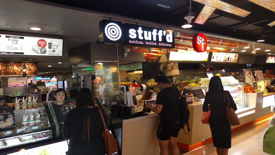 An interior view of Stuffd, a food stall, showing customers at the counter and menu boards.