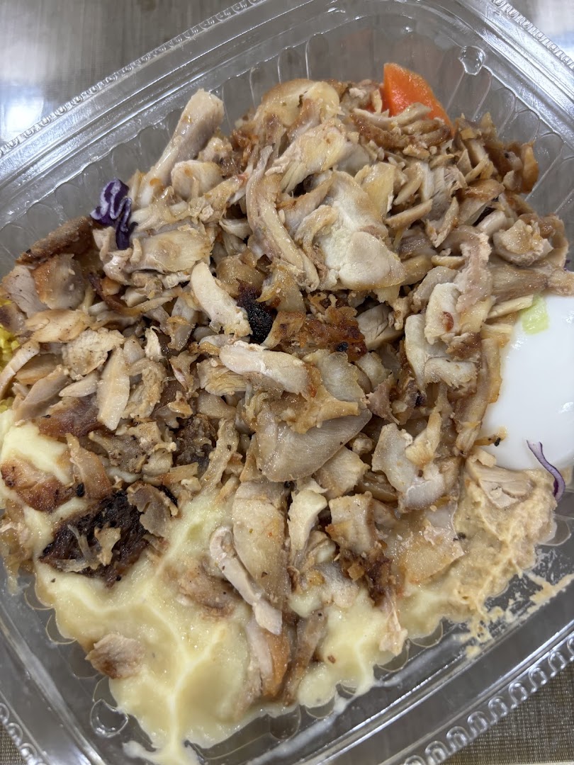 A close-up of a Stuffd chicken bowl with shredded meat over a creamy base in a clear container.