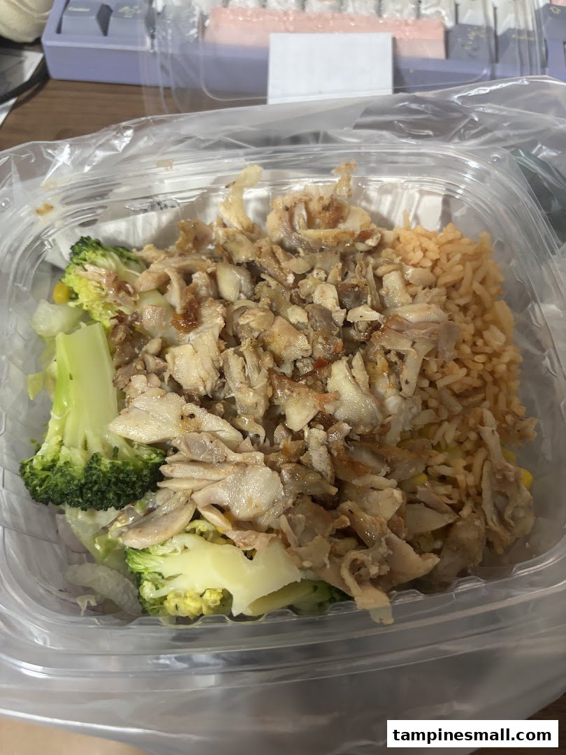 A close-up of a Stuffd meal bowl featuring shredded meat, rice, and broccoli in a clear plastic container.