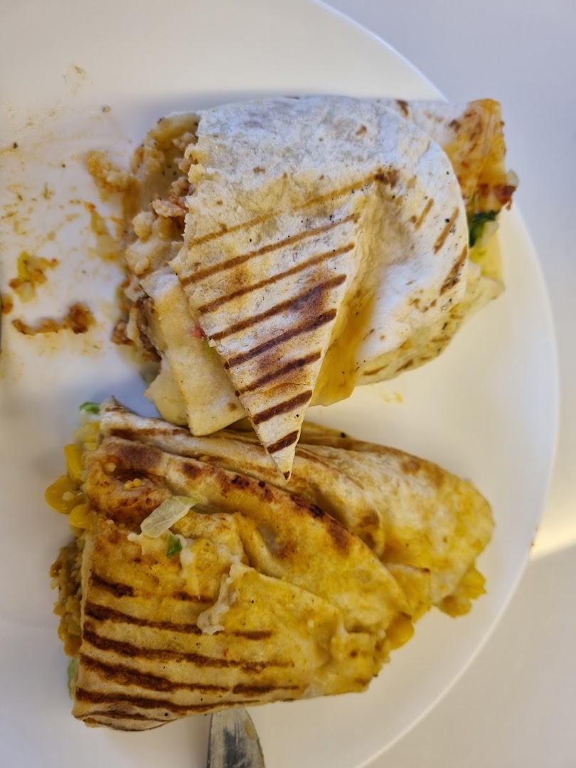 Close-up of a grilled wrap or quesadilla, cut in half, served on a white plate.