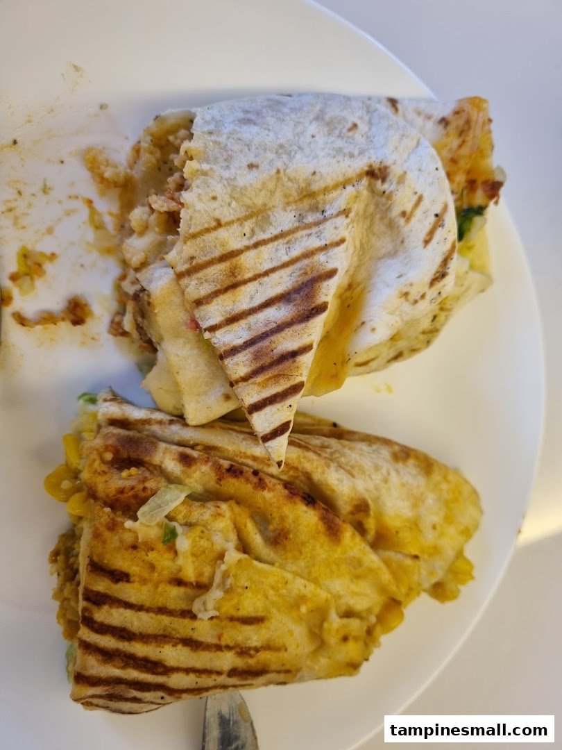 Close-up of a grilled wrap or quesadilla, cut in half, served on a white plate.