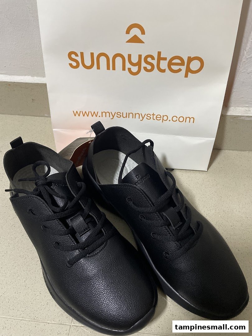 A pair of black Sunnystep shoes next to a branded shopping bag.