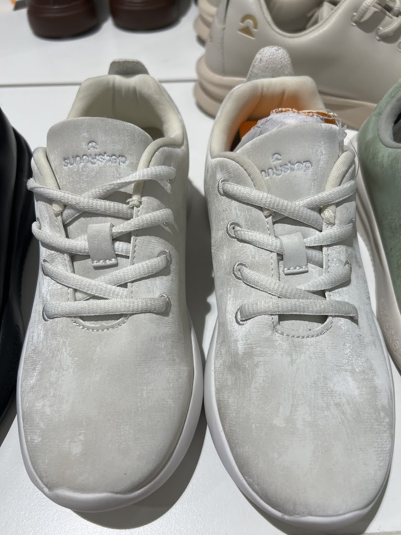 A close-up view of two pairs of light-colored Sunnystep sneakers on display.