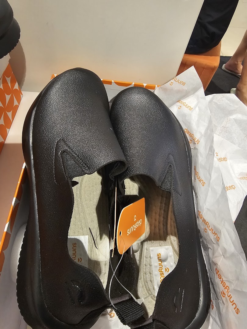 A new pair of black slip-on shoes from Sunnystep, still in their box with branding visible.