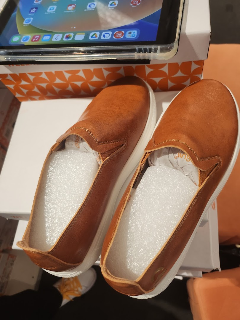 A pair of new brown slip-on shoes with white soles, displayed on a box, possibly a recent purchase.