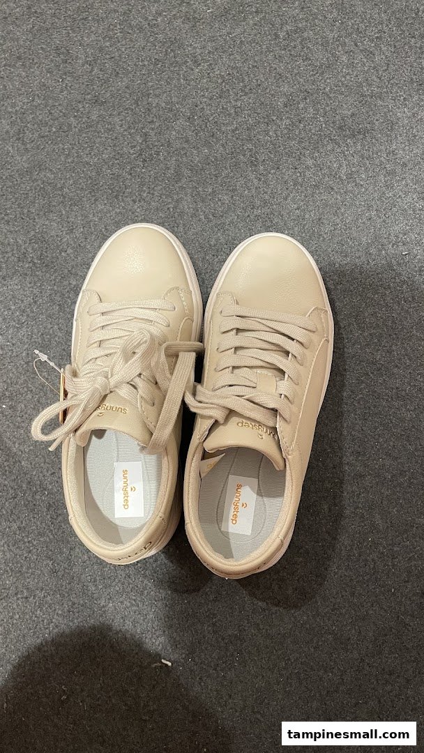 A pair of new beige Sunnystep sneakers with tags on a dark grey floor.