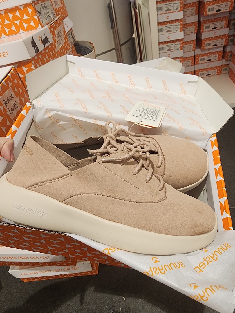 A pair of beige Sunnystep shoes in their box, showcasing the brand's footwear.