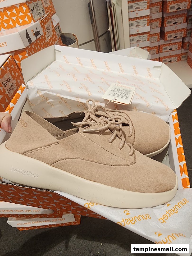 A pair of beige Sunnystep shoes in their box, showcasing the brand's footwear.