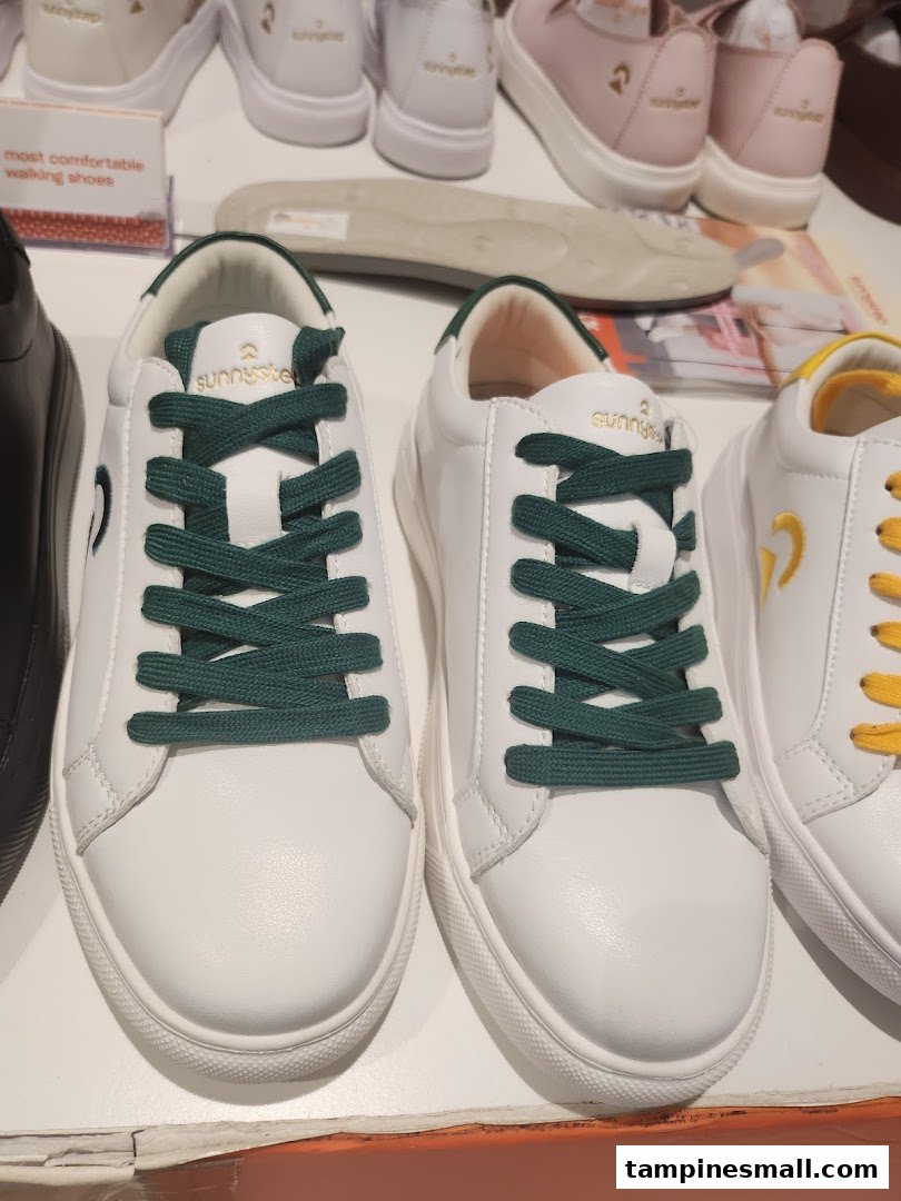 Close-up of white Sunnystep sneakers with dark green laces on display.