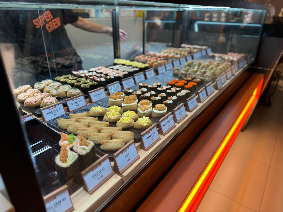 A vibrant display case showcasing a wide variety of fresh sushi and inari at Super Sushi.
