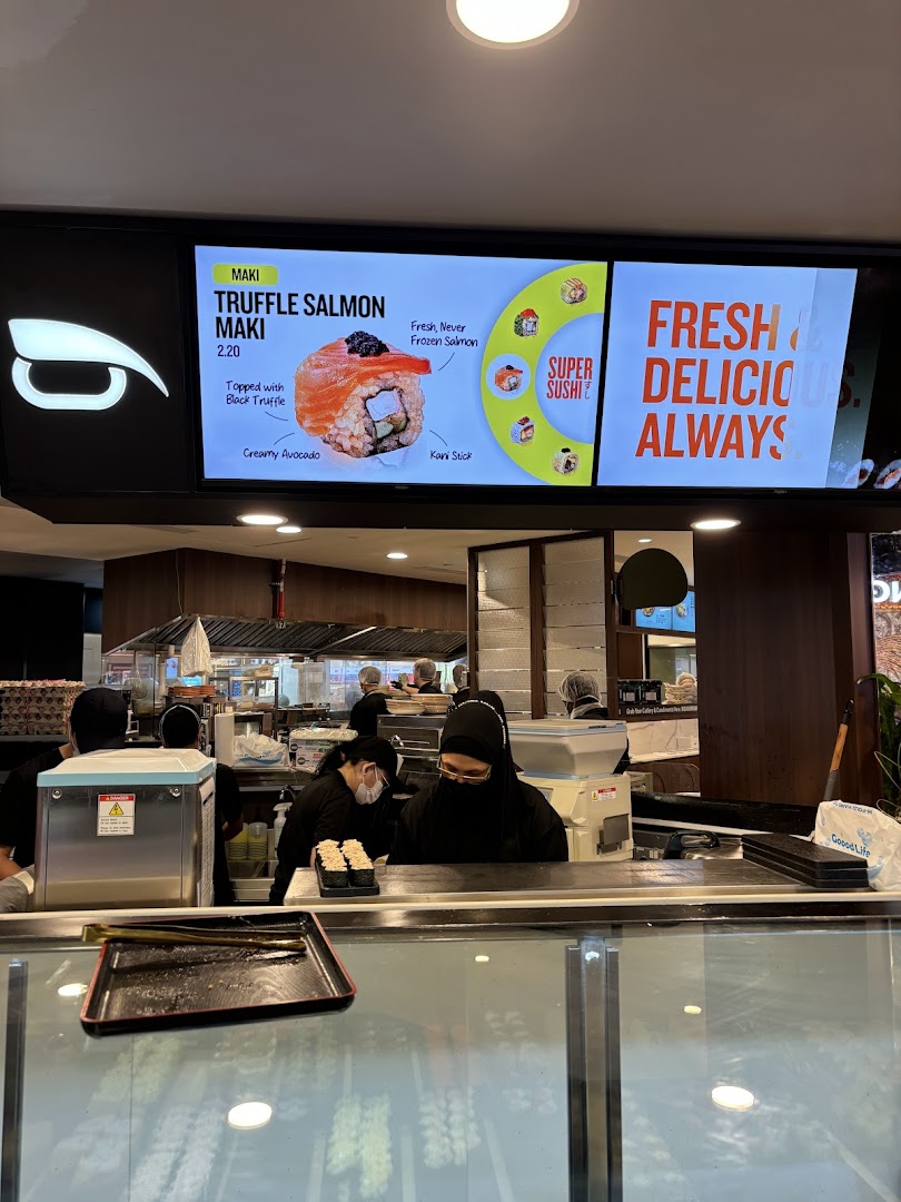 Interior view of Super Sushi with staff preparing food and a digital menu displaying Truffle Salmon Maki.