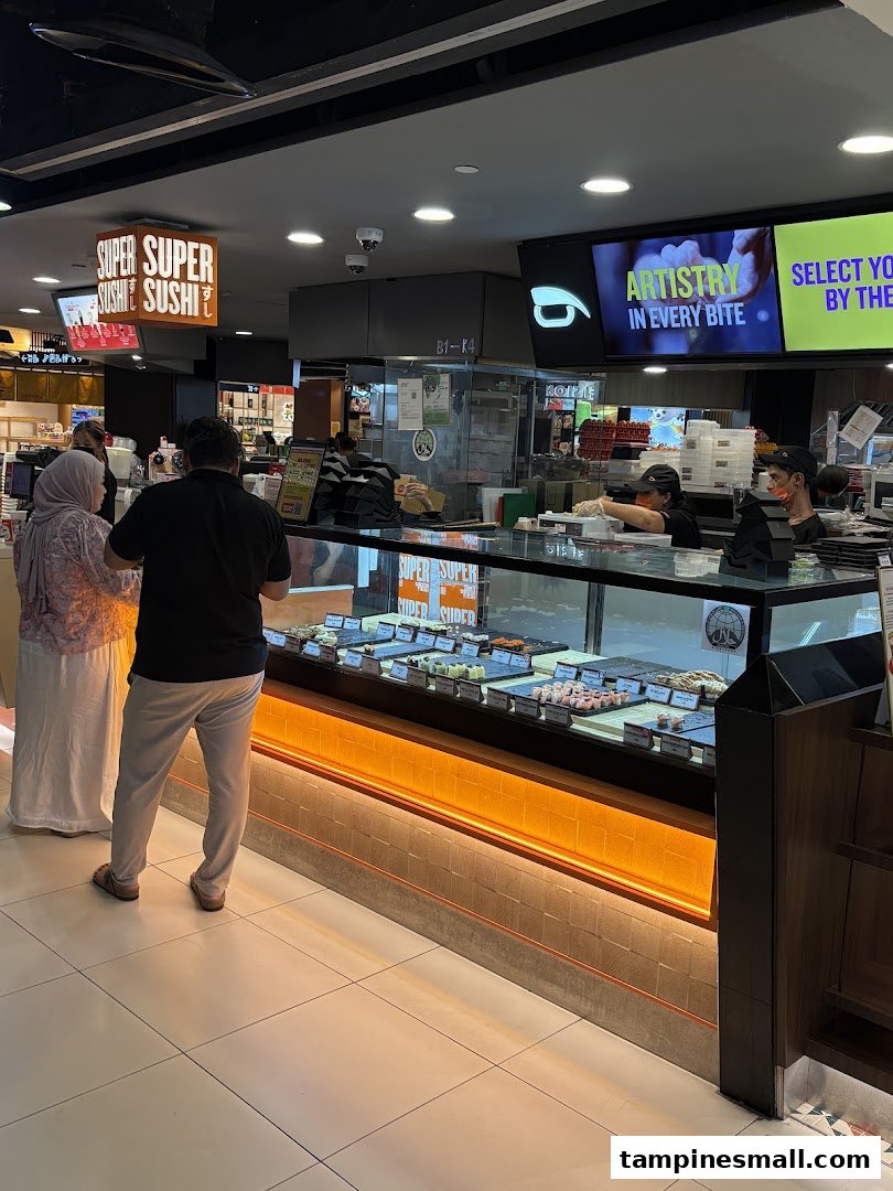 Interior view of Super Sushi with customers, staff, and a sushi display counter.