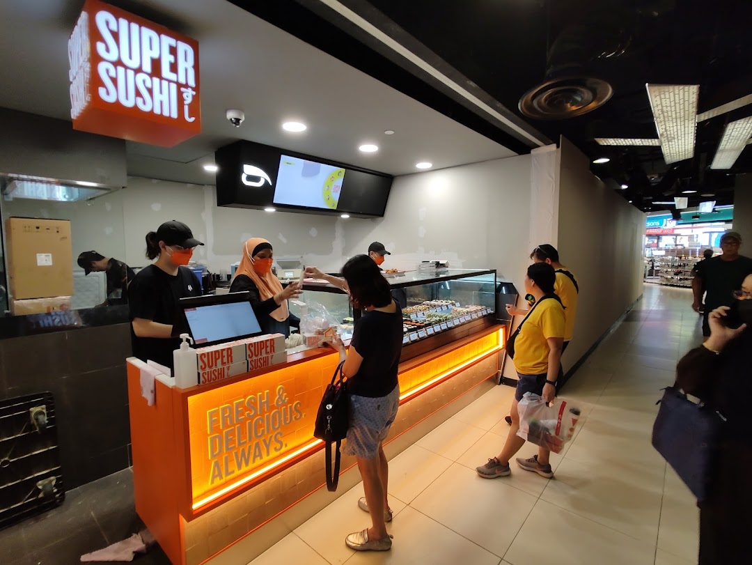Customers interact with staff at the Super Sushi counter, featuring a display of fresh sushi and a 'Fresh & Delicious. Always.' sign.