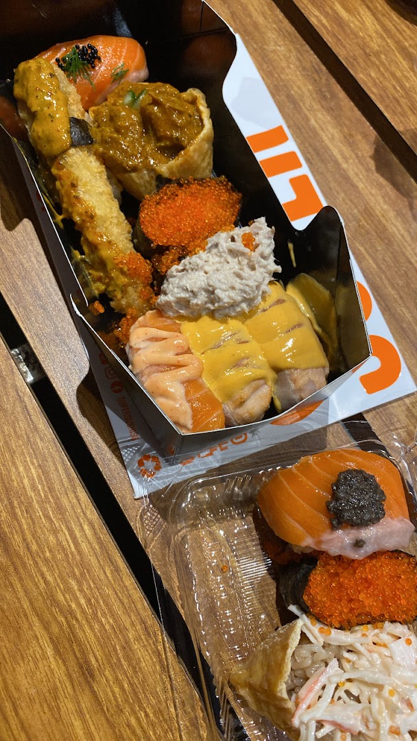 A vibrant assortment of sushi and Japanese dishes in takeaway packaging from Super Sushi.
