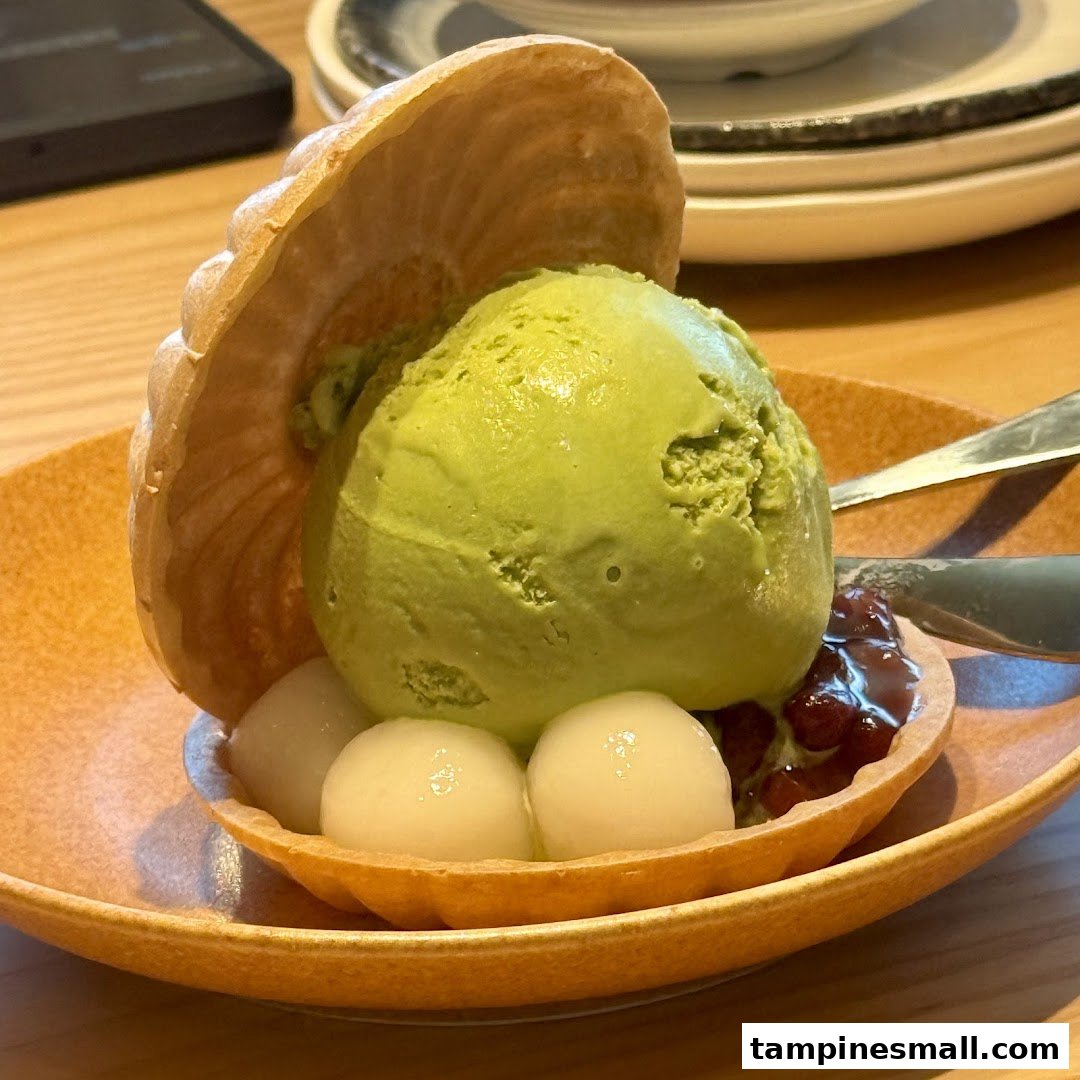 A vibrant green tea ice cream dessert with mochi, red bean paste, and a waffle crisp.