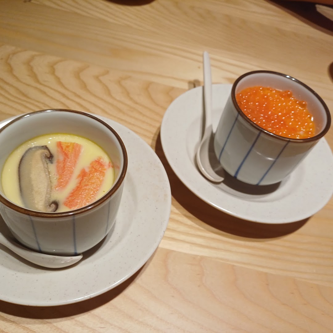 Two Japanese dishes, chawanmushi and ikura, served in traditional cups on a wooden table.