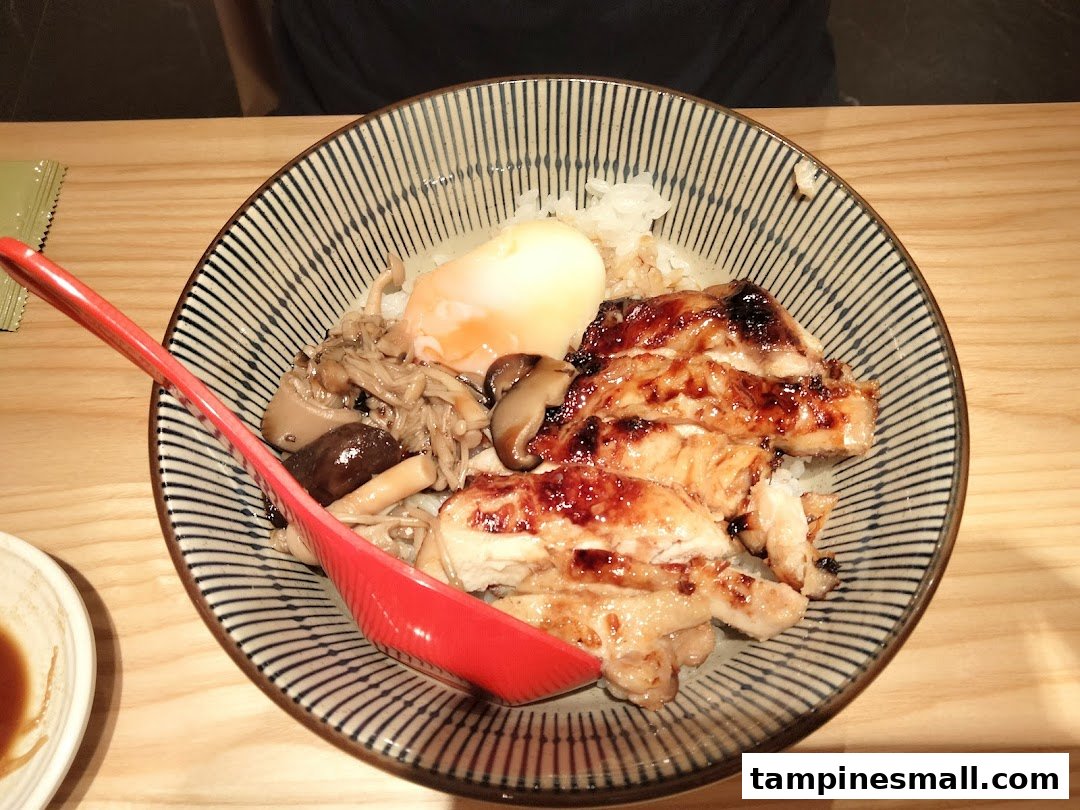 A delicious Japanese rice bowl featuring grilled chicken, assorted mushrooms, and a soft-boiled egg.