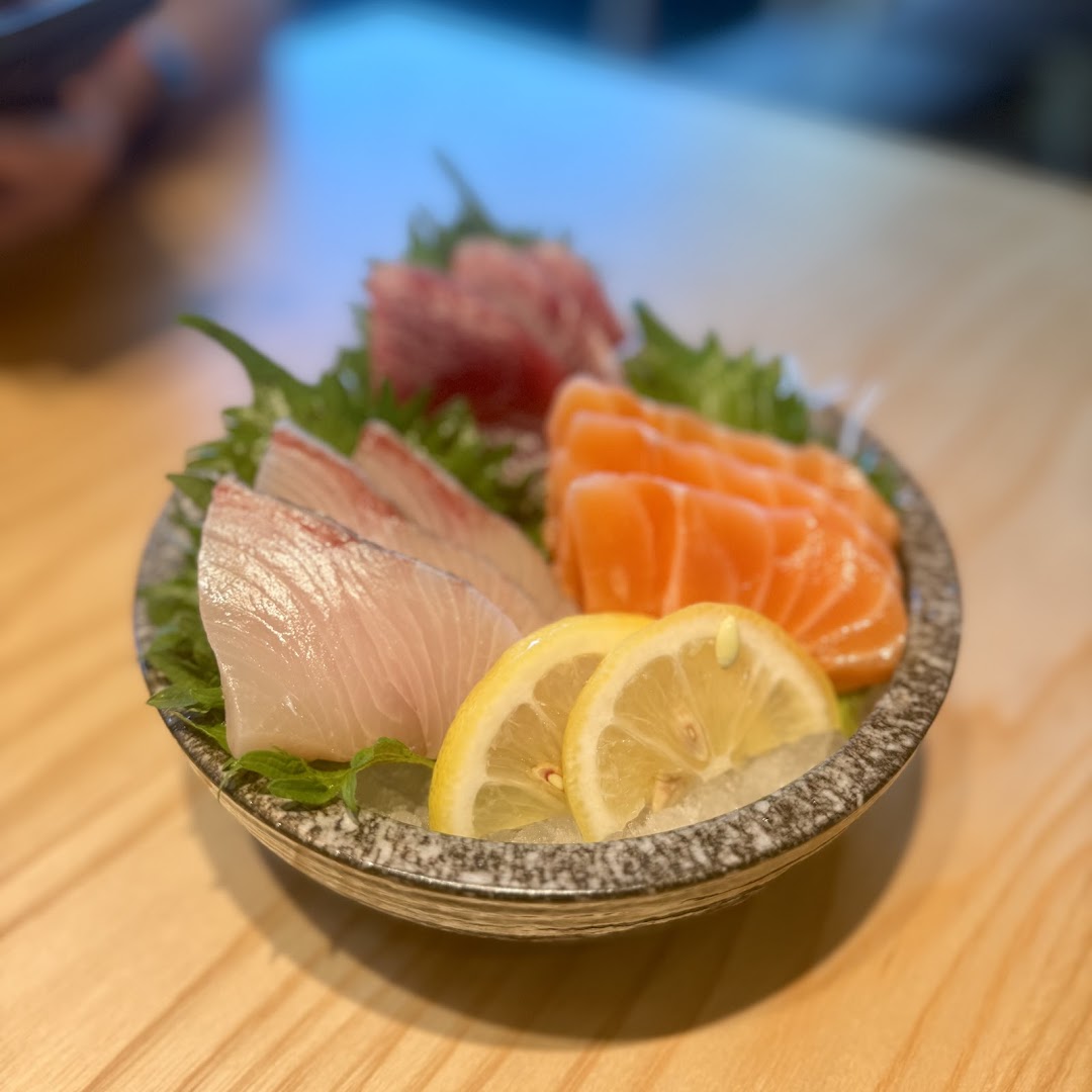 A vibrant plate of fresh sashimi featuring salmon, white fish, and tuna, garnished with lemon.
