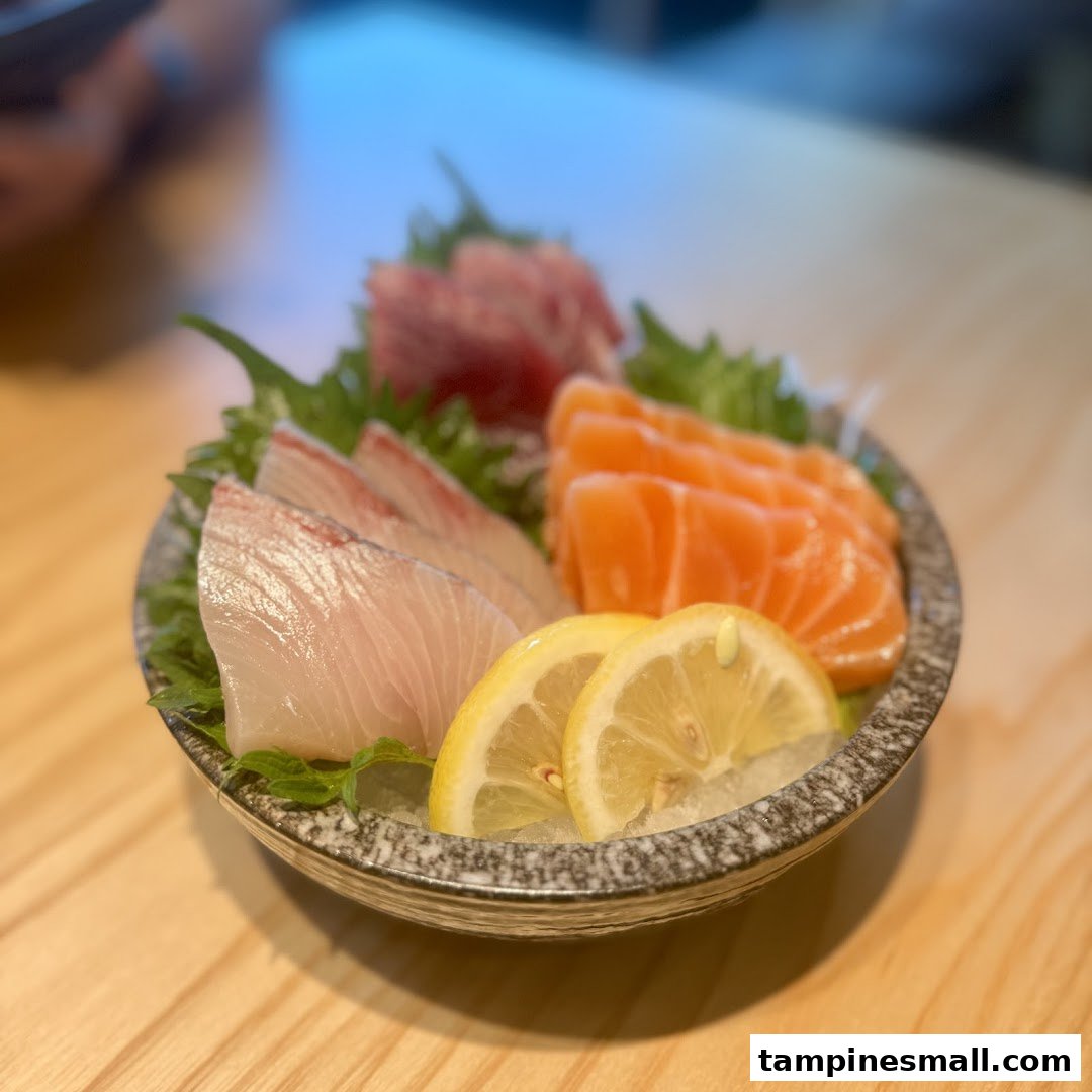 A vibrant plate of fresh sashimi featuring salmon, white fish, and tuna, garnished with lemon.