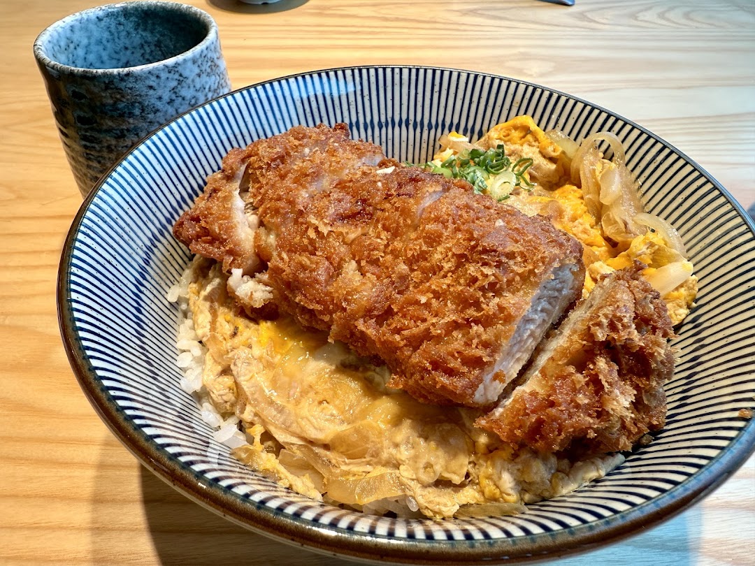 A delicious Katsu Don featuring crispy fried cutlet, egg, and onions served in a patterned bowl.
