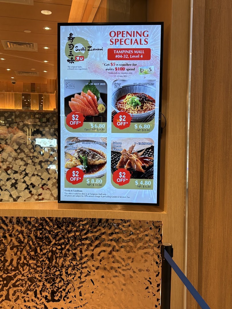 A digital display at Sushi Zanmai's entrance showcasing opening specials and discounted menu items.