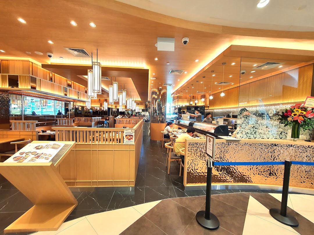 Spacious, modern interior of Sushi Zanmai featuring a sushi bar, dining tables, and staff.