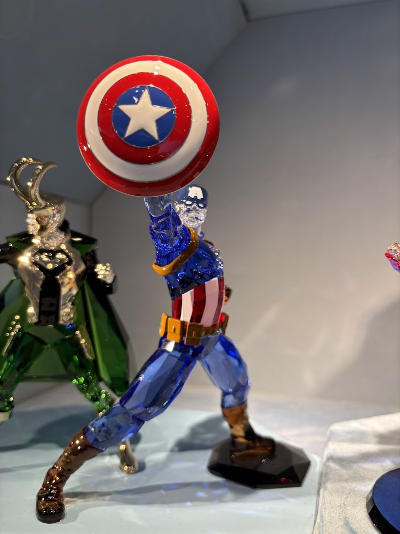 A detailed crystal figurine of Captain America with his shield, displayed in a Swarovski store.