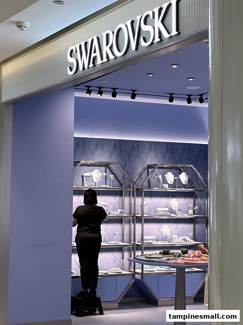 The image shows the entrance of a Swarovski store with a staff member inside arranging displays.