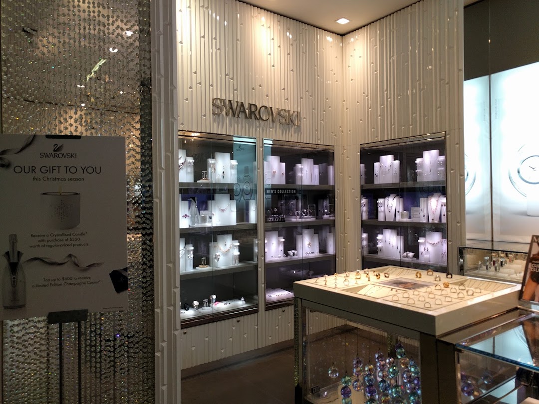 Interior view of Swarovski store showcasing sparkling crystal jewelry displays and a festive promotion.