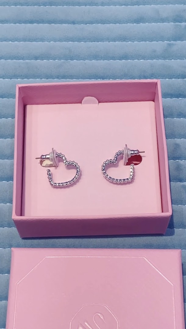 A pair of sparkling heart-shaped earrings displayed in a pink Swarovski gift box.