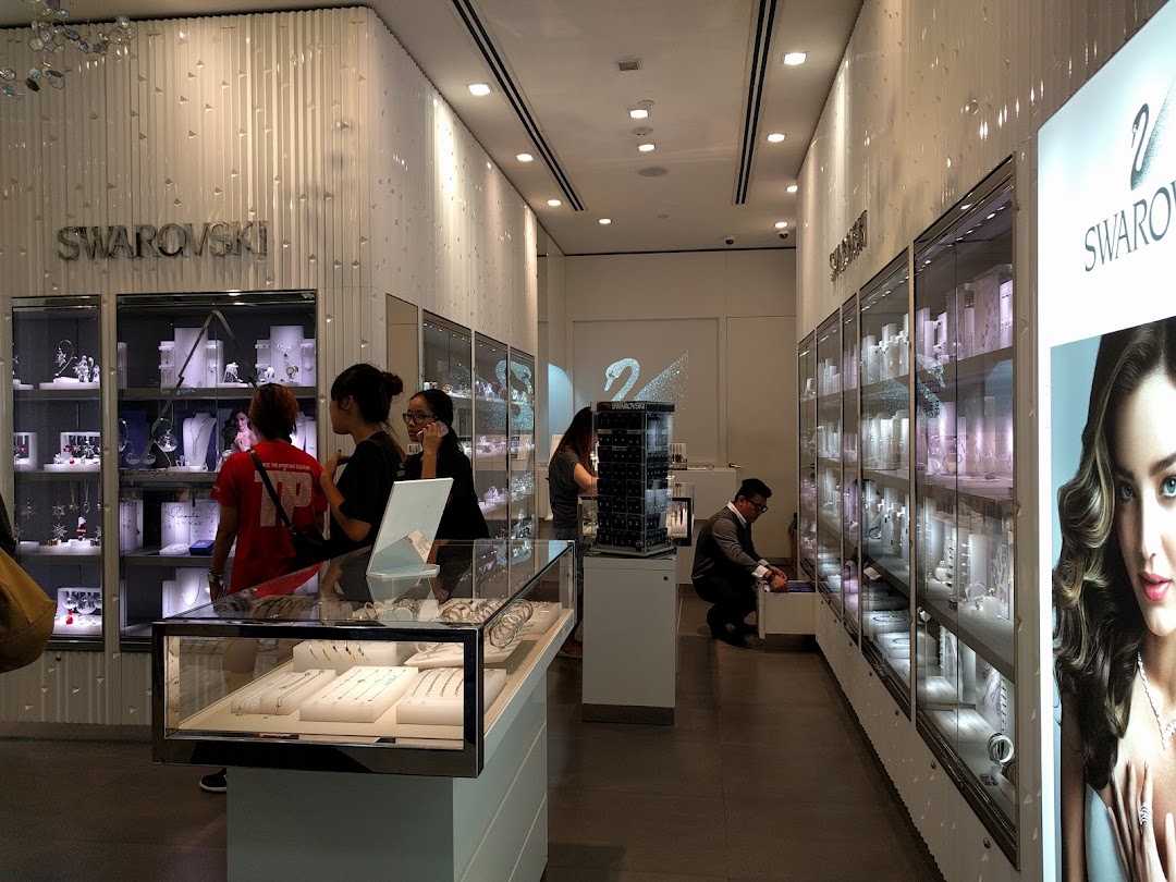 Interior view of a modern Swarovski store showcasing sparkling jewelry displays and customers browsing.