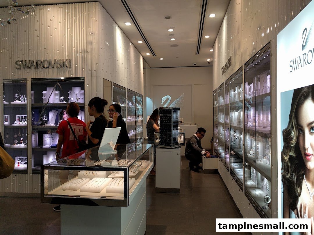 Interior view of a modern Swarovski store showcasing sparkling jewelry displays and customers browsing.