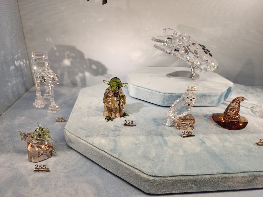 Close-up of various Swarovski crystal figurines, including Star Wars and Harry Potter characters, displayed in a store.