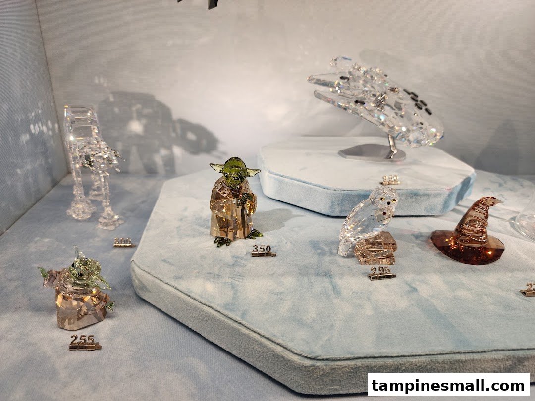 Close-up of various Swarovski crystal figurines, including Star Wars and Harry Potter characters, displayed in a store.