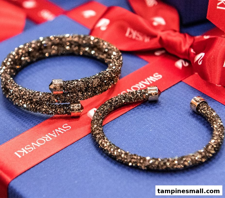 Two sparkling Swarovski crystal bracelets displayed on a blue gift box with a red branded ribbon.
