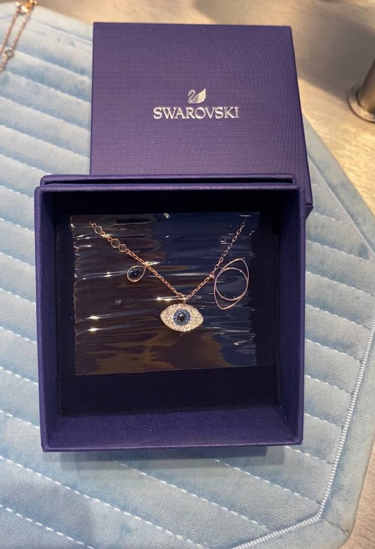 A rose gold-tone Swarovski necklace with an evil eye pendant in its signature blue box.