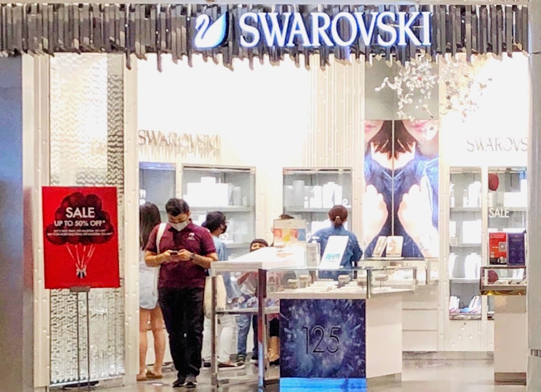 The entrance of Swarovski at Tampines Mall, featuring a sale sign and customers browsing sparkling jewelry.
