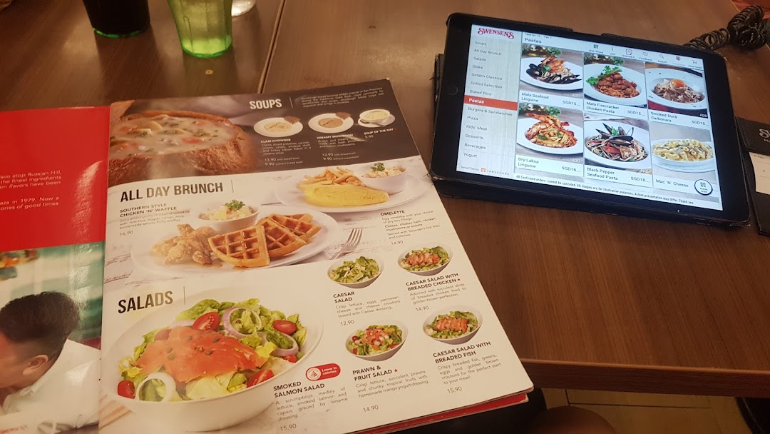 A table view showing a physical menu book and a digital menu tablet at Swensen's.