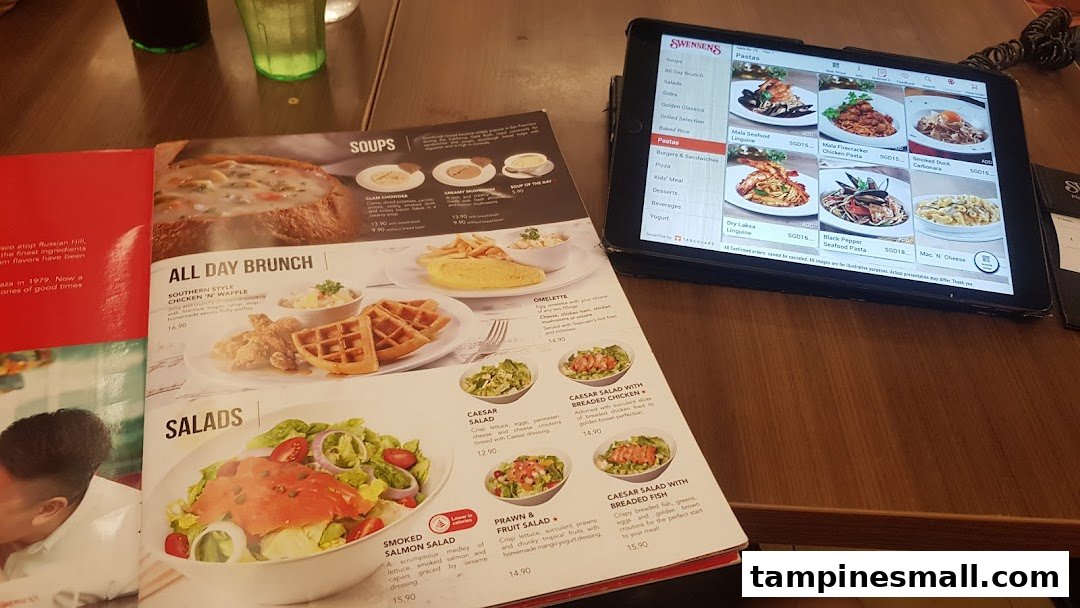 A table view showing a physical menu book and a digital menu tablet at Swensen's.