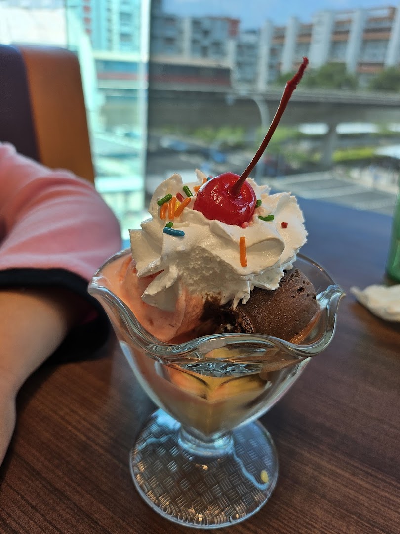 A delicious ice cream sundae with whipped cream, sprinkles, and a cherry, served at Swensen's.