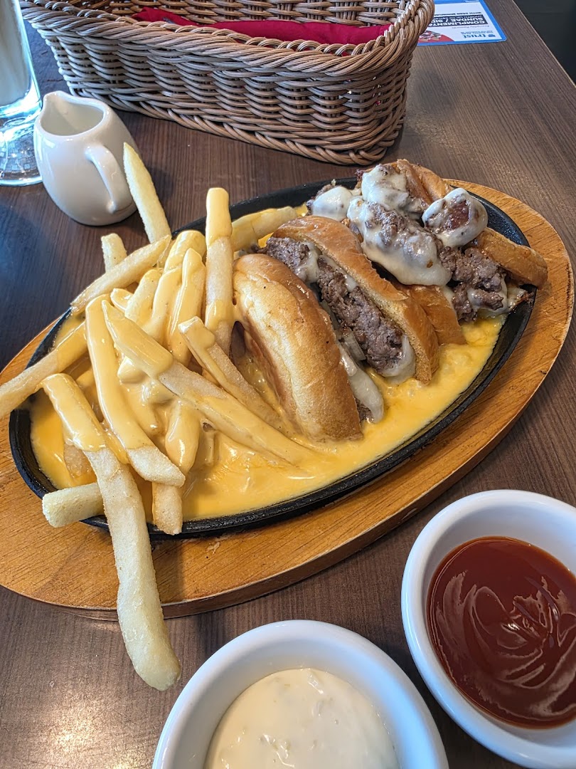 A sizzling plate of cheesy fries and mini burgers, served with dipping sauces.