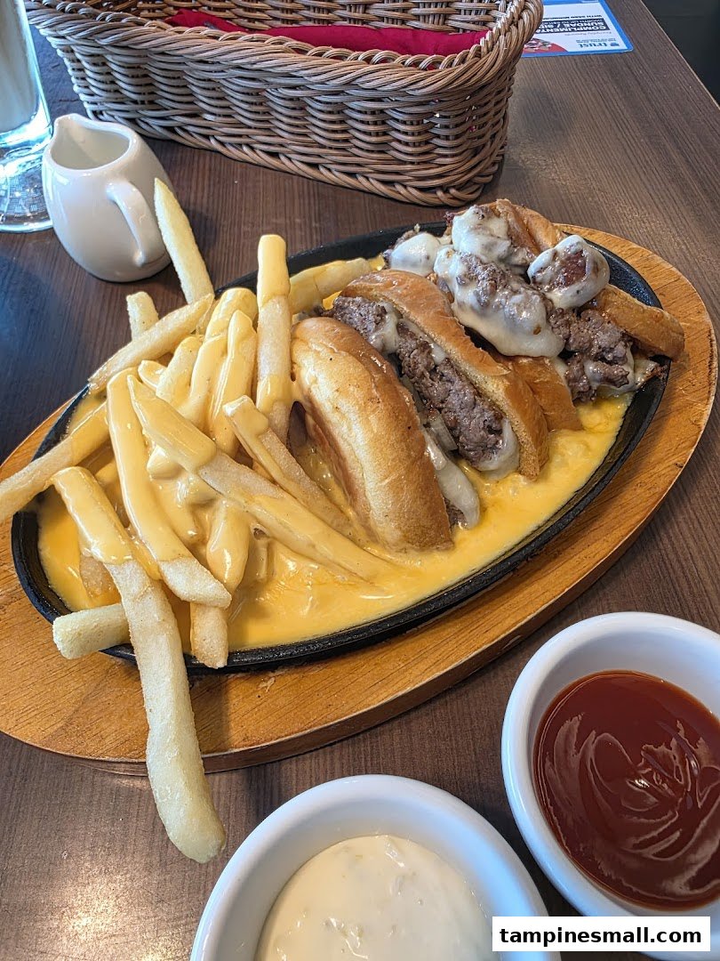 A sizzling plate of cheesy fries and mini burgers, served with dipping sauces.