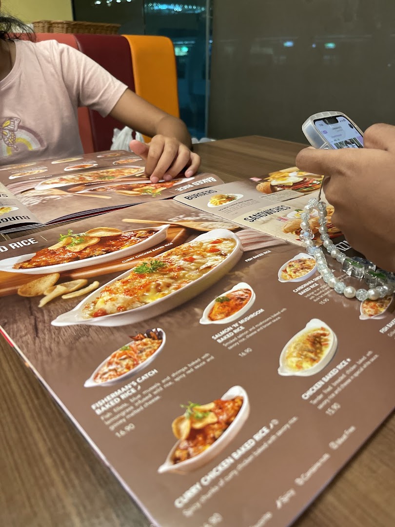 Customers at Swensen's Tampines Mall browse a menu featuring various baked rice dishes.